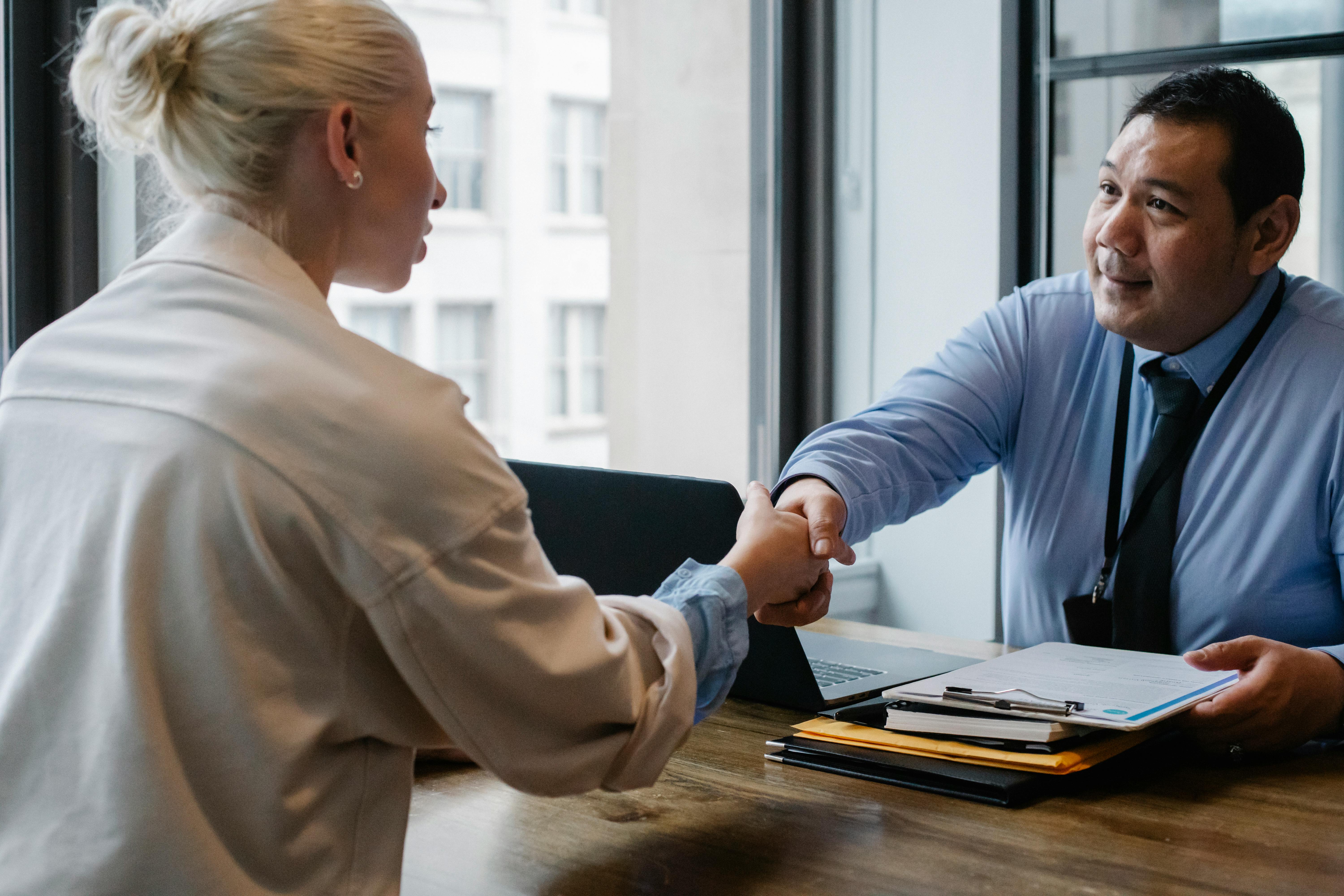 Photo depicts woman facing away from the camera shaking a man's hand