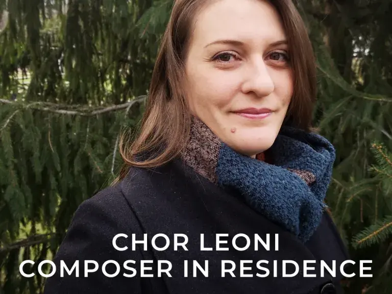 A photo of Marie-Claire Saindon, standing in front of a tree in a jacket, wearing a scarf. She is looking at the camera and smiling. The text on the image reads CHOR LEONI COMPOSER IN RESIDENCE Marie-Claire Saindon