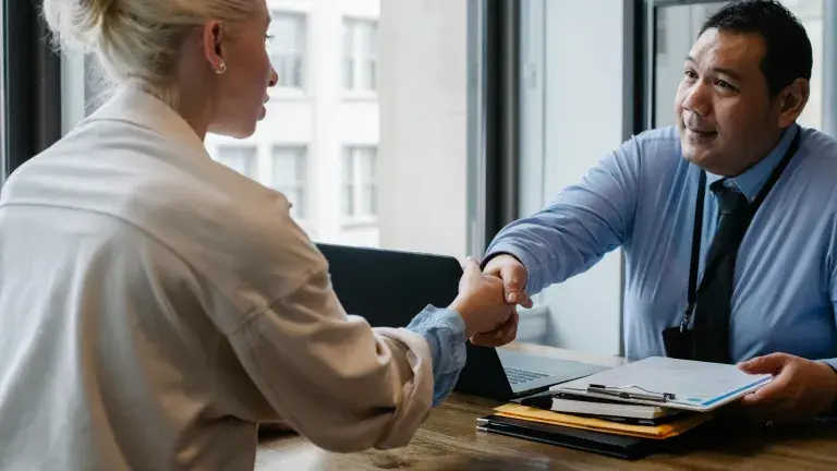 Photo depicts woman facing away from the camera shaking a man's hand