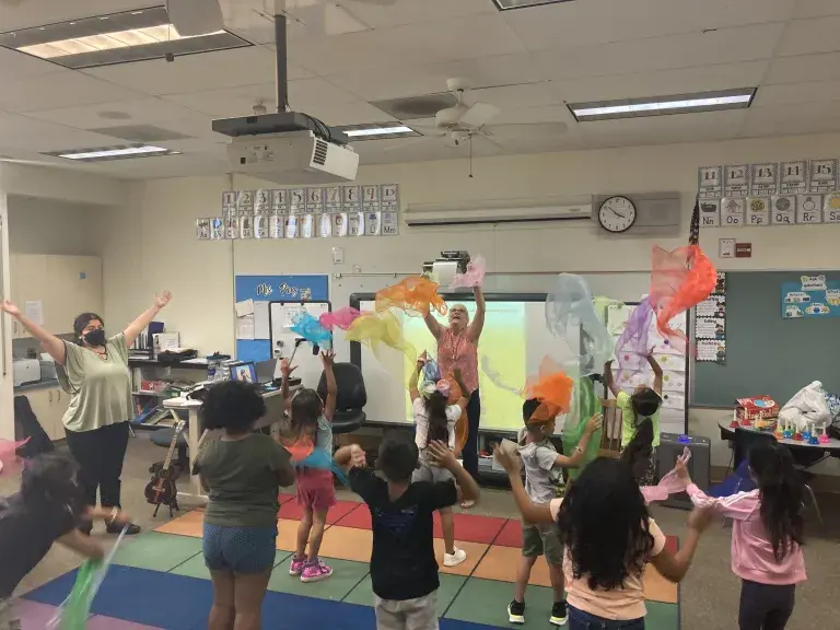 Students in a classroom playing with scarves. 