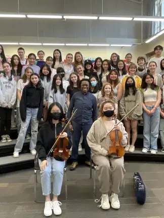 Student singers and string players posing for a photo.