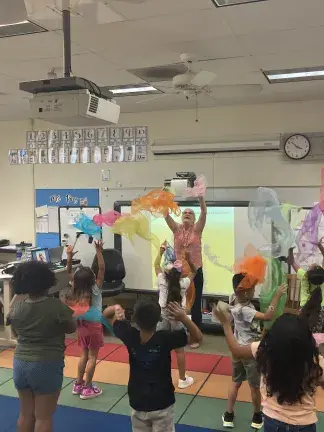 Students in a classroom playing with scarves. 