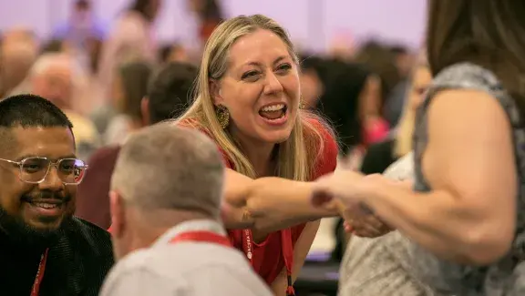 woman reaching across table to shake hands with another woman