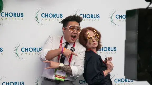 two people standing back to back posing for a camera