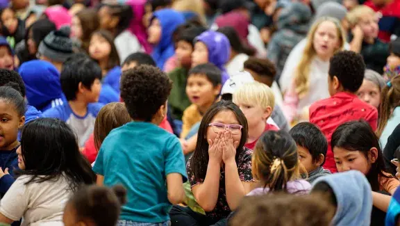 girl laughing in crowd of other children