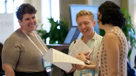 three people talking and looking at sheet music